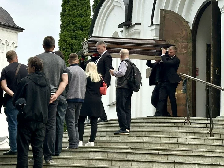 People gathered around a hearse, ready to depart for the cemetery
