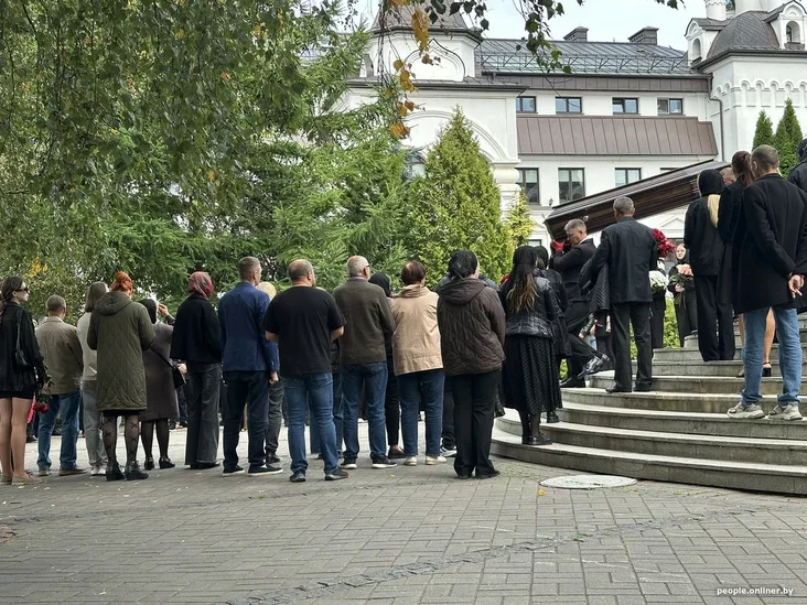 Mourners standing outside the church, some still holding flowers