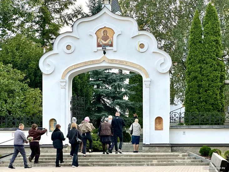 People gathered in a church for a funeral, some holding flowers